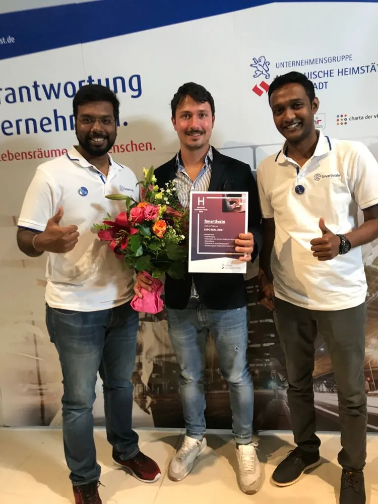 Smartivate co-founders in company polo shirts with the hubitation finals 2018 winner certificate and a bouquet.